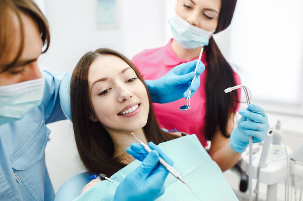 Schonsee Dental relaxed patient smiling during a checkup with dentist and assistant in Edmonton